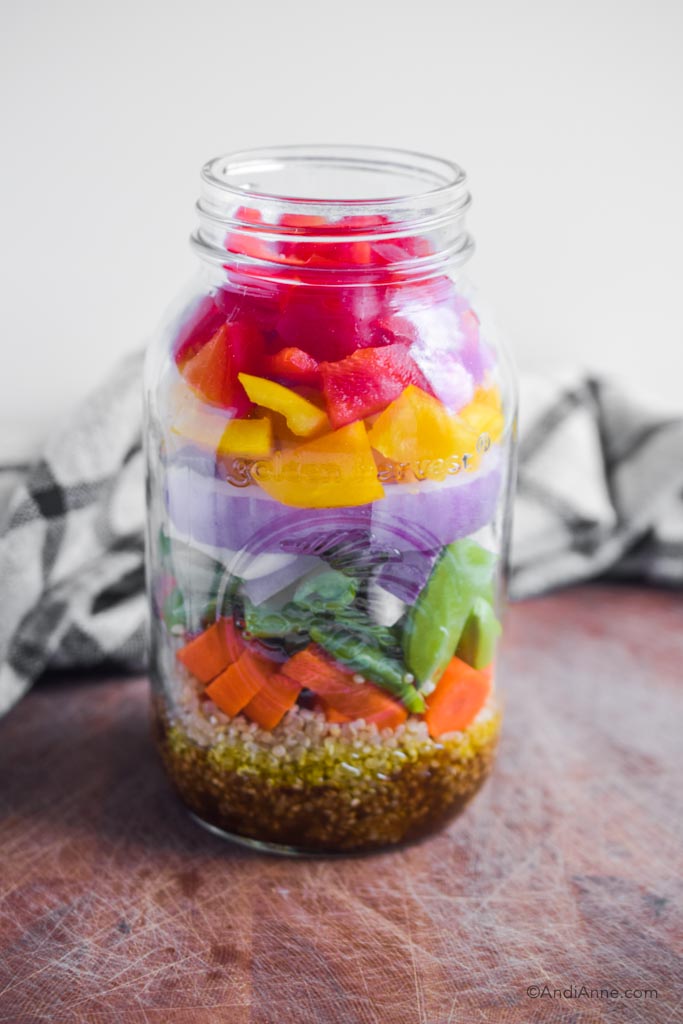 rainbow mason jar salad on cutting board with kitchen towel in background