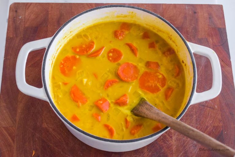 carrot ginger turmeric soup in a white pot.