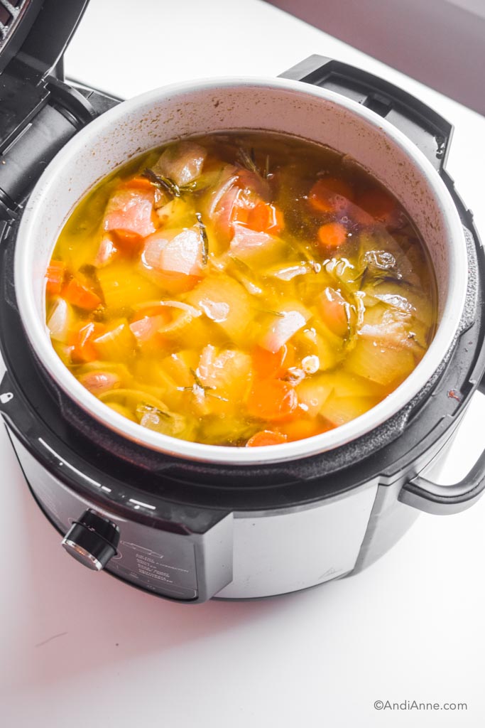 Looking into an instant pot with cooked vegetables and water.