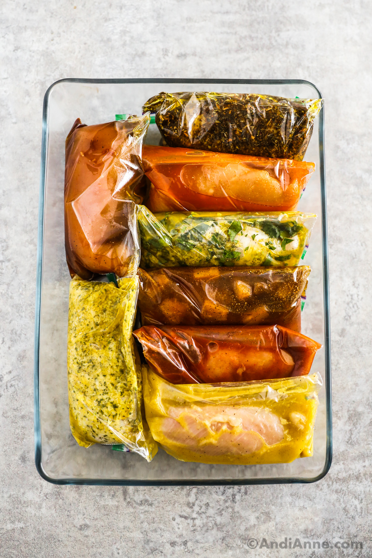 A casserole dish with bags of different chicken marinades in various flavors