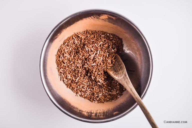 shredded coconut and cacao powder in a metal bowl with wooden spoon