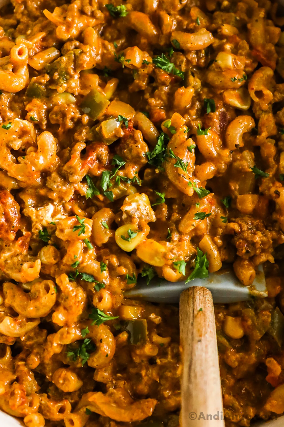 Close up of taco pasta where you can see the spiral pasta noodles, corn, tomato and bits of parsley, all in a creamy tomato sauce.