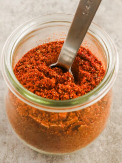 A jar of taco seasoning with a spoon in it