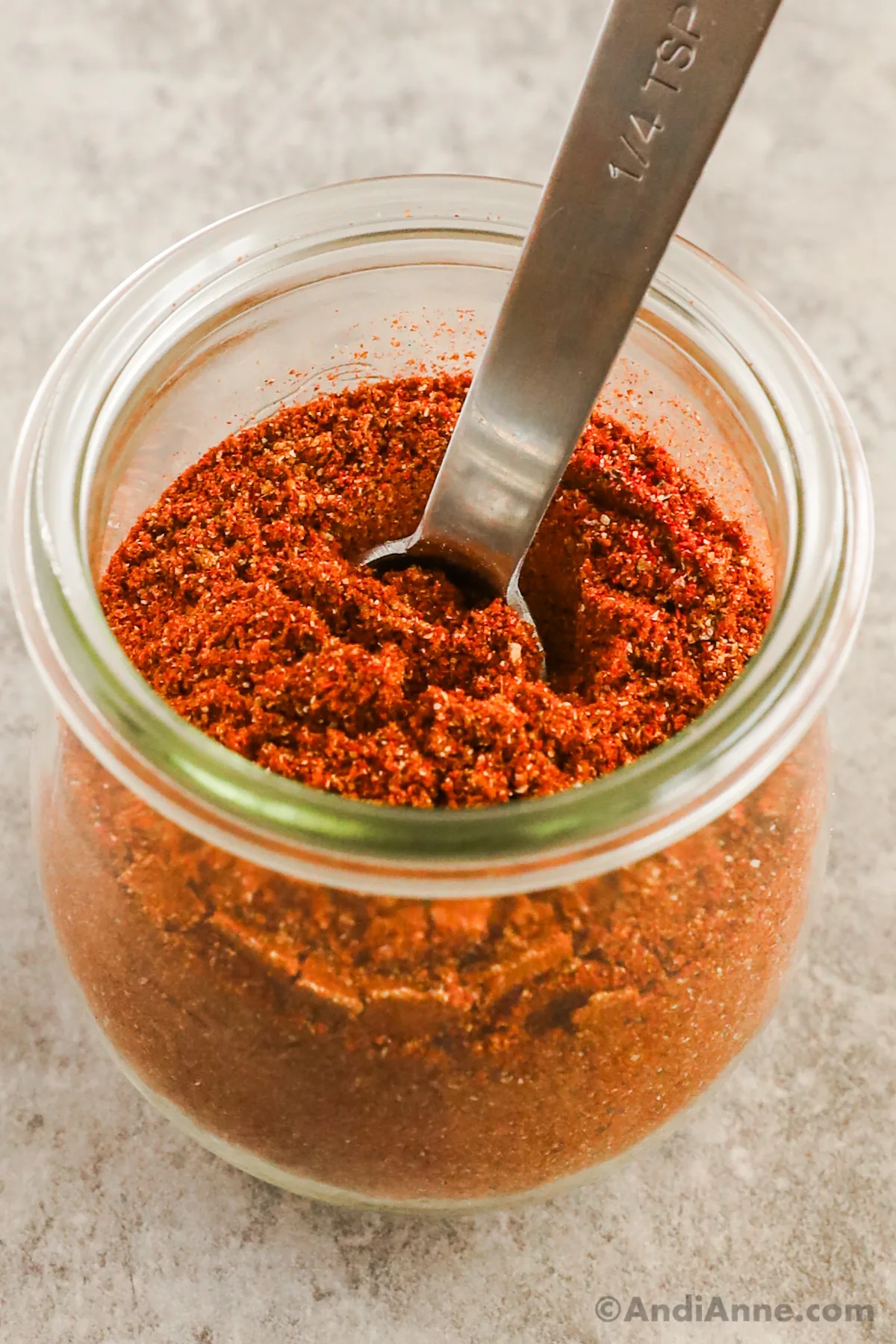 A jar of taco seasoning mix with a spoon inside.