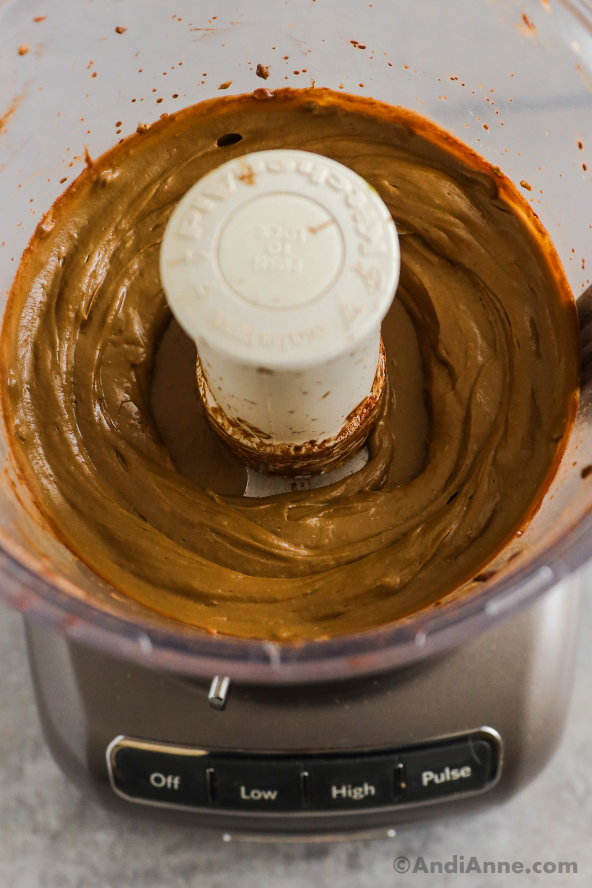 A food processor with smooth creamy chocolate avocado pudding inside.