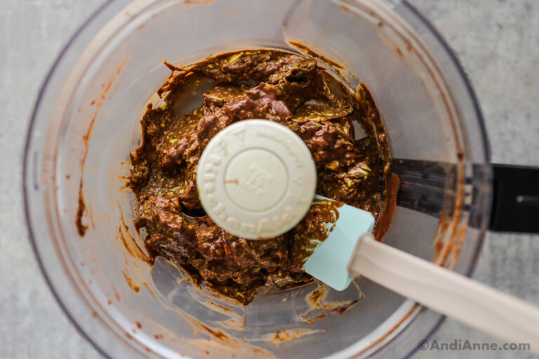 Chocolate mixture in a food processor container with a spatula.