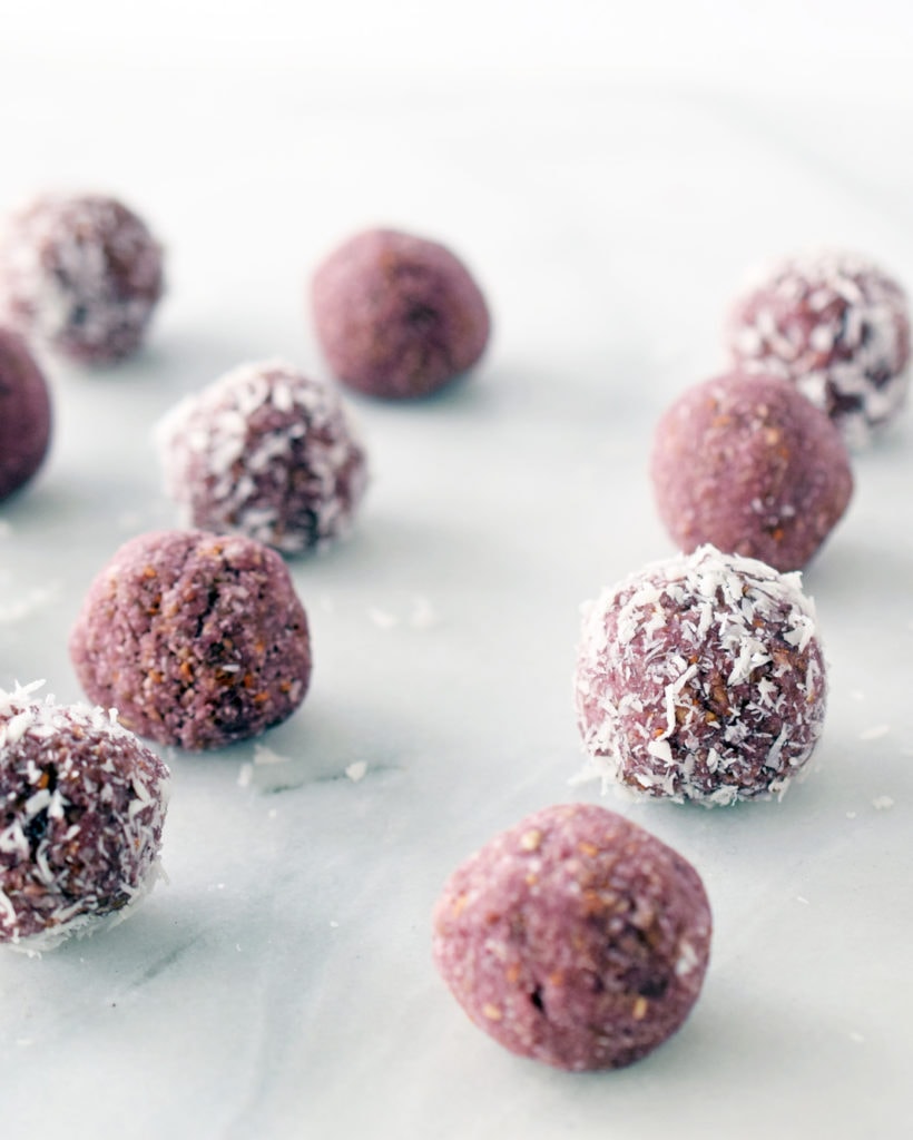 raspberry coconut energy balls on a marble counter placed in rows