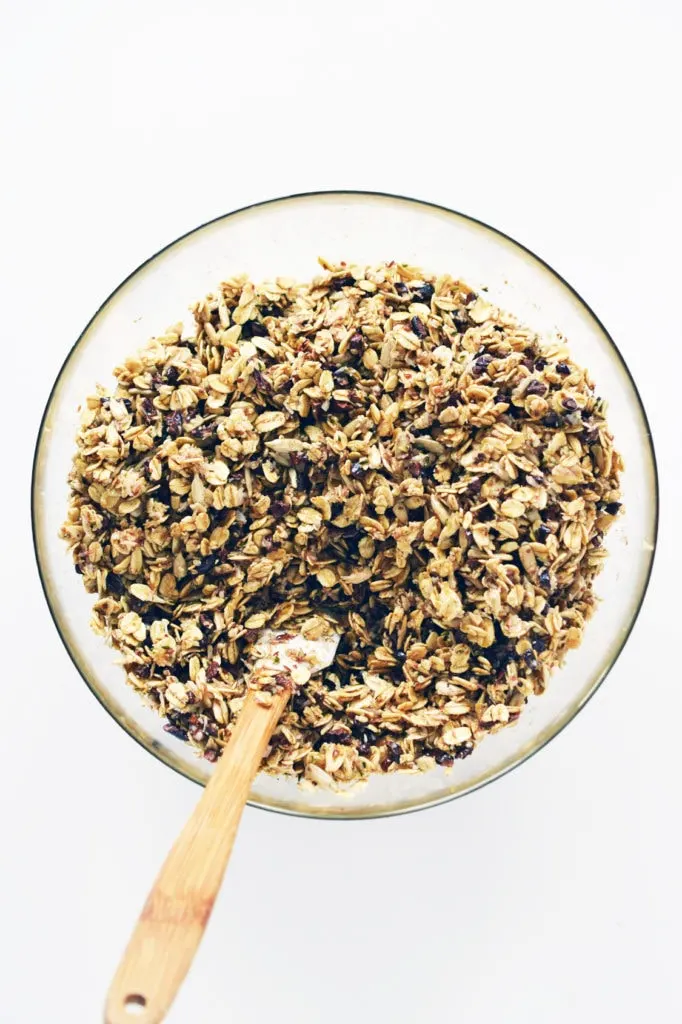 glass bowl holding mixture of superfood granola with small spatula