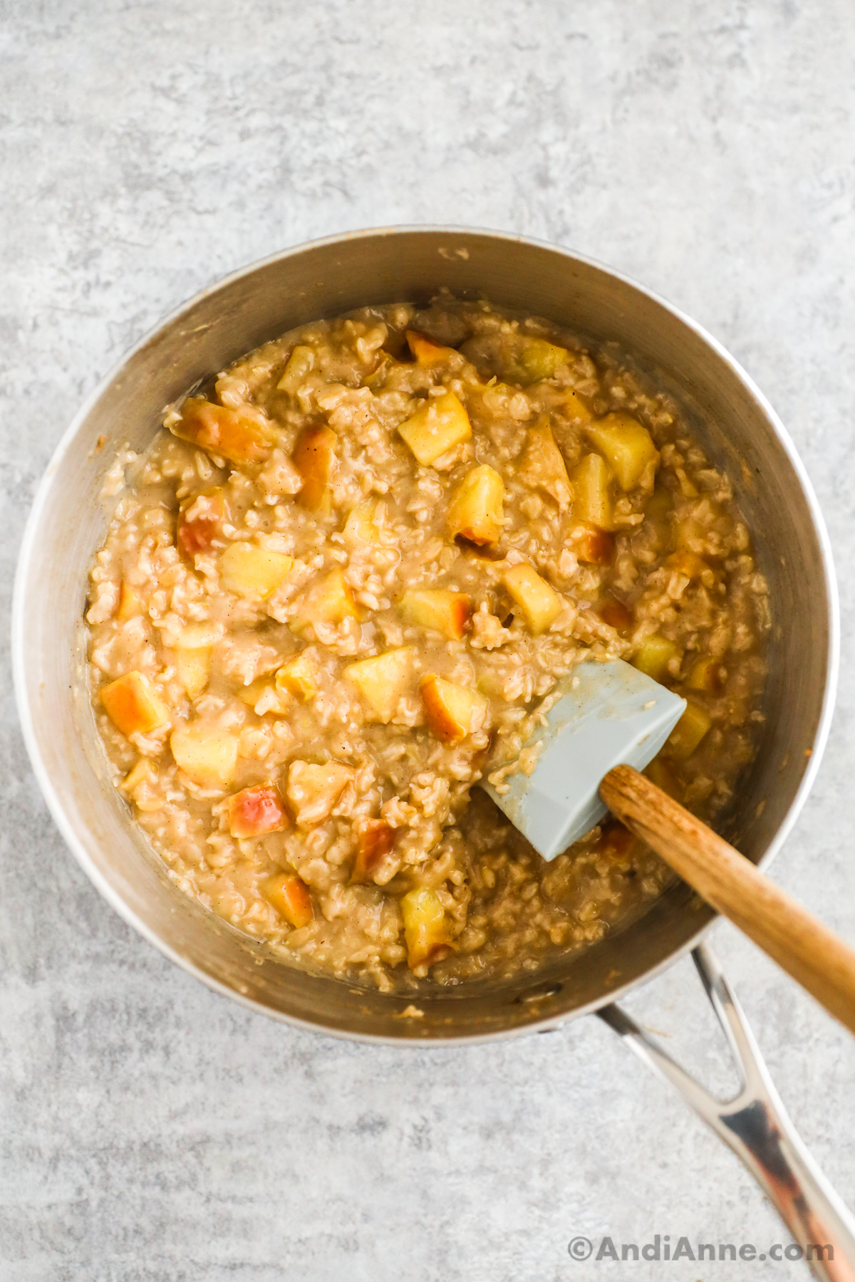A pot of cooked apple cinnamon oatmeal with a spatula.