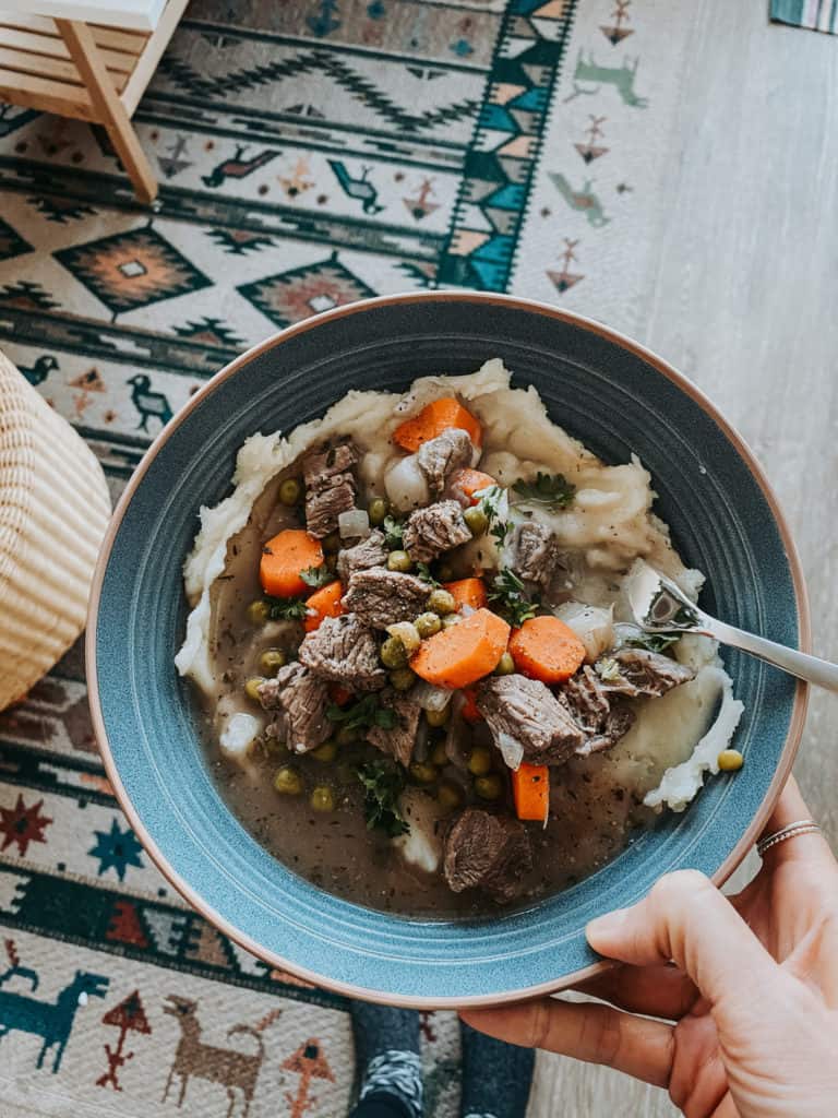 Slow Cooker Beef Stew With Mashed Potatoes in a blue bowl with patterned carpet in background