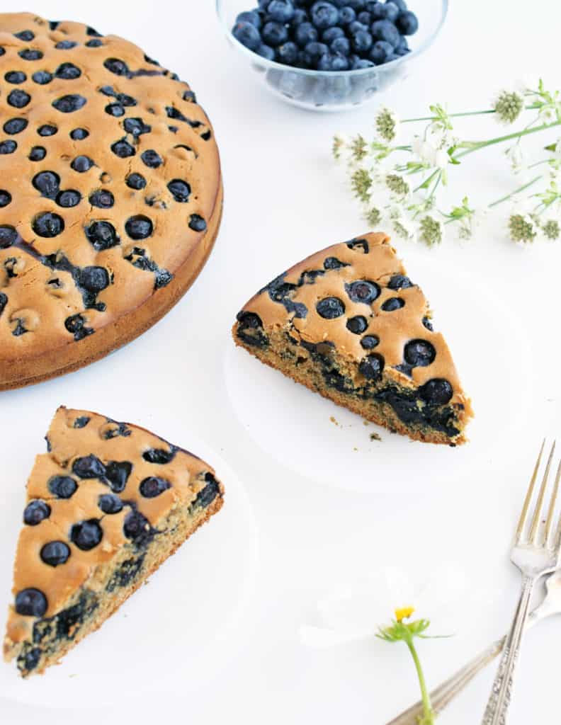 Slices of gluten free blueberry cake on plates with serving forks