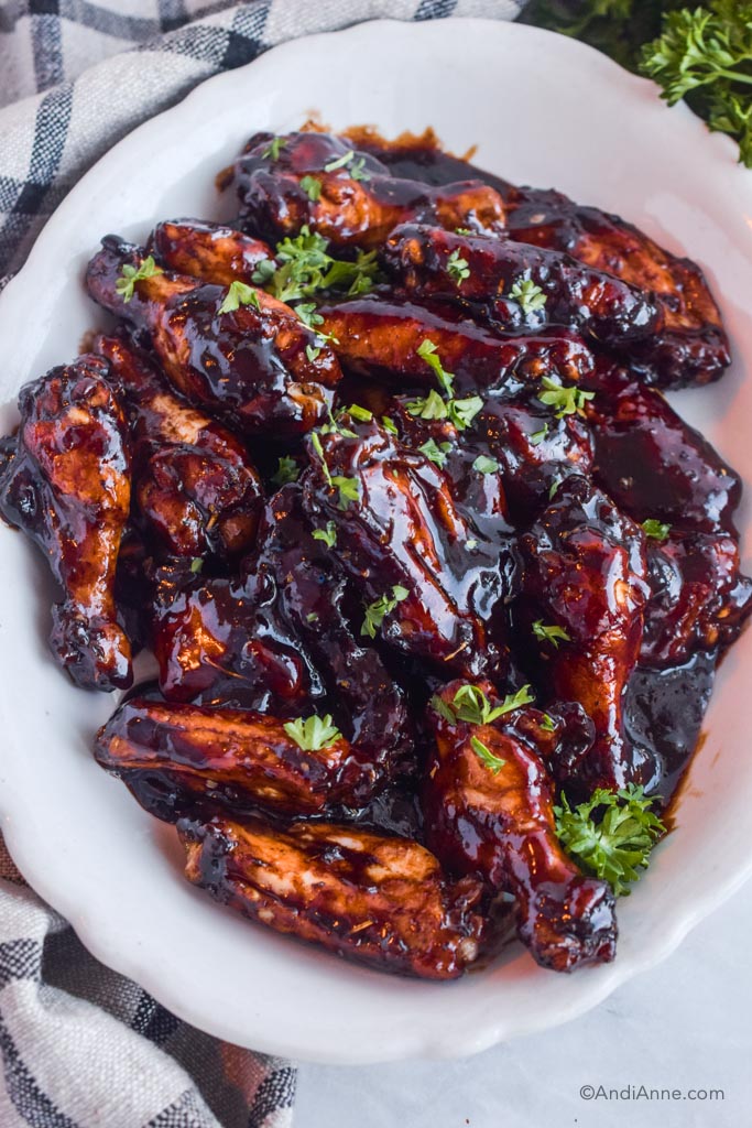 balsamic chicken wings in a white dish with parsley sprinkled on top. 