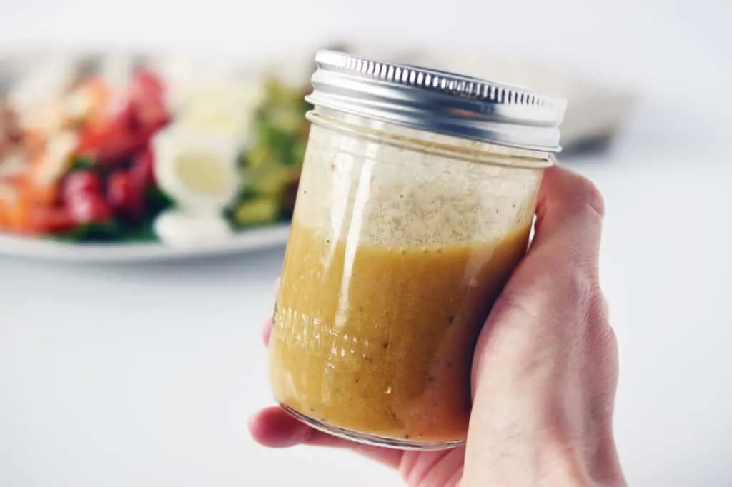 hand holding mason jar of salad dressing