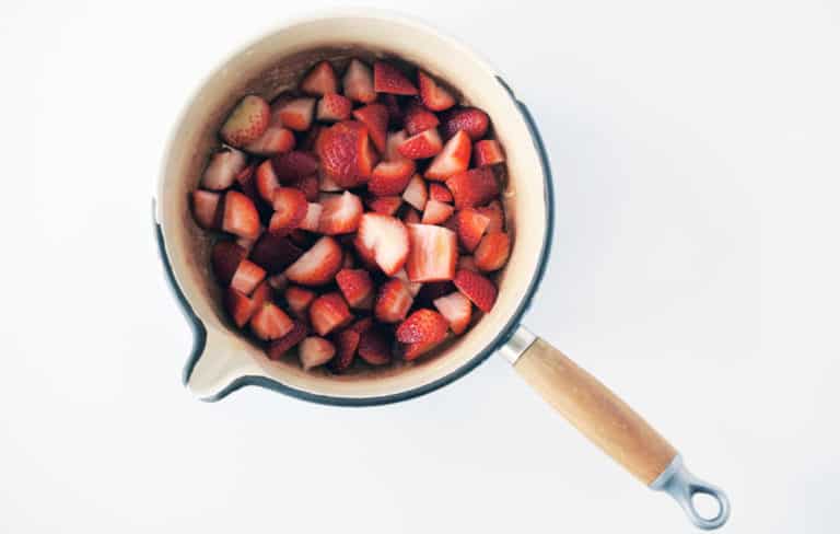 sliced strawberries in a pot with wood handle