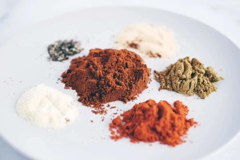 white, brown and red spices all separated on a grey plate