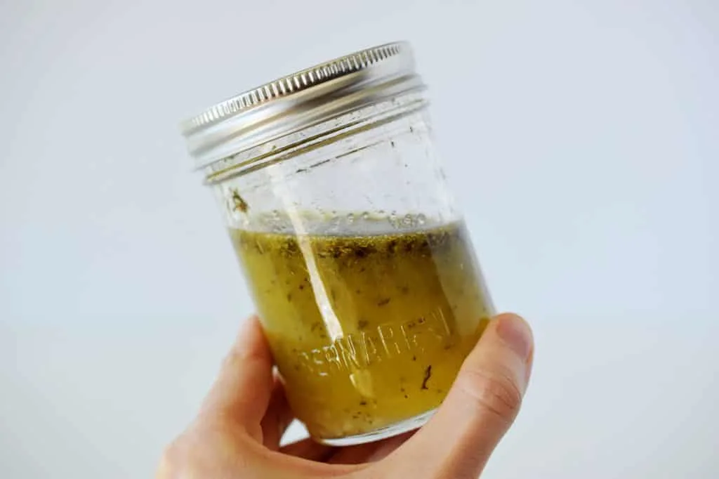 mason jar with lid held in a hand with salad dressing inside