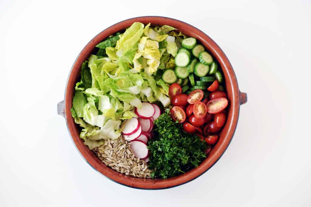 garden salad ingredients separated in a brown bowl