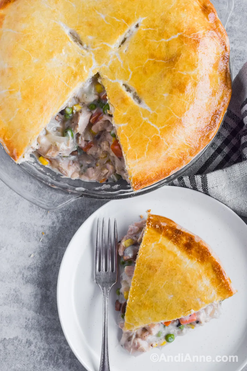 Baked turkey pot pie with a slice on a white plate with a fork.