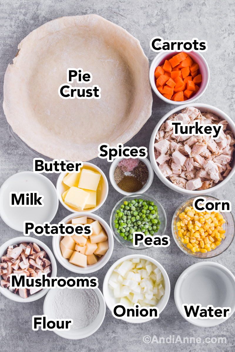 Ingredients to make recipe on counter including pie crust, chopped turkey, bowl of corn, peas, potatoes, mushroom and flour.