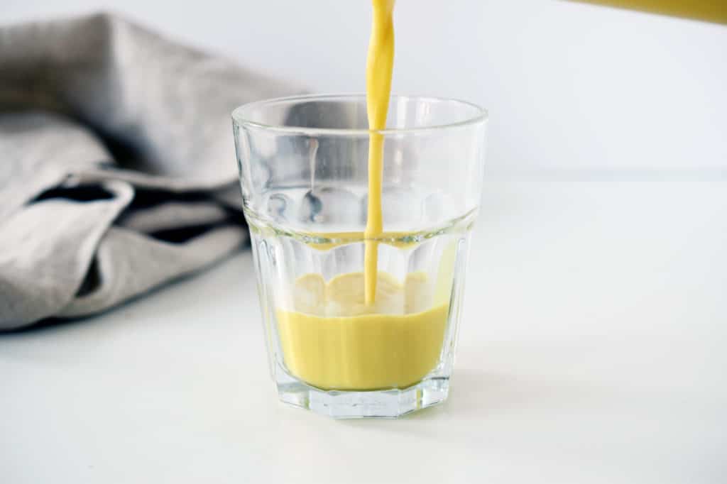 pouring turmeric ginger latte into a glass jar