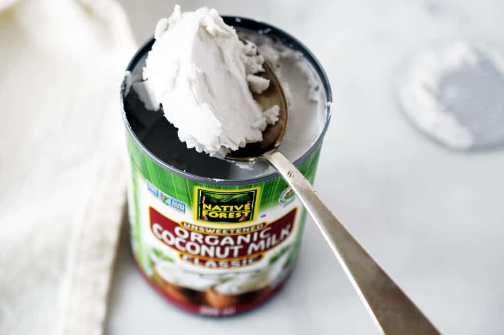 Spoon scooping out coconut cream from a can of coconut milk