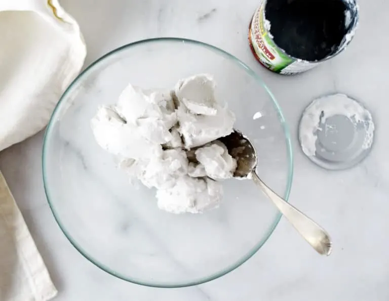 coconut cream scooped into glass bowl with empty can on right and white napkin on left