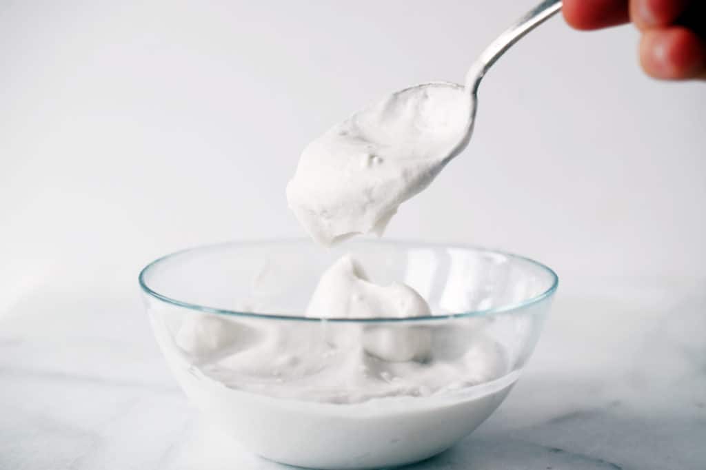 glass bowl filled with whipped coconut cream. Spoon scooping it out.