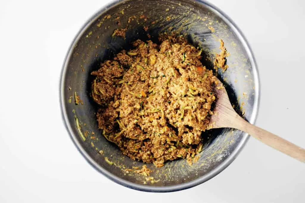 muffin batter in a steel bowl with wooden spoon