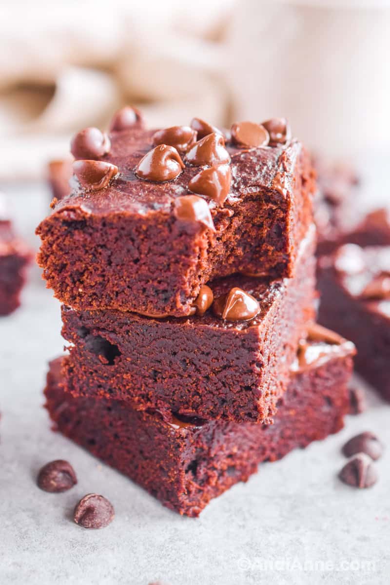 Three brownies piled on top of eachother with chocolate chips on top.