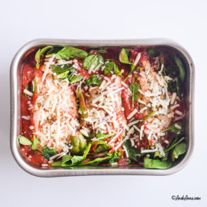 fresh mozzarella cheese and raw spinach are sprinkled on top of the chicken in tomato sauce