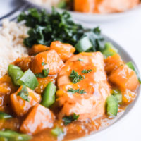 A plate of orange chicken, rice and greens.