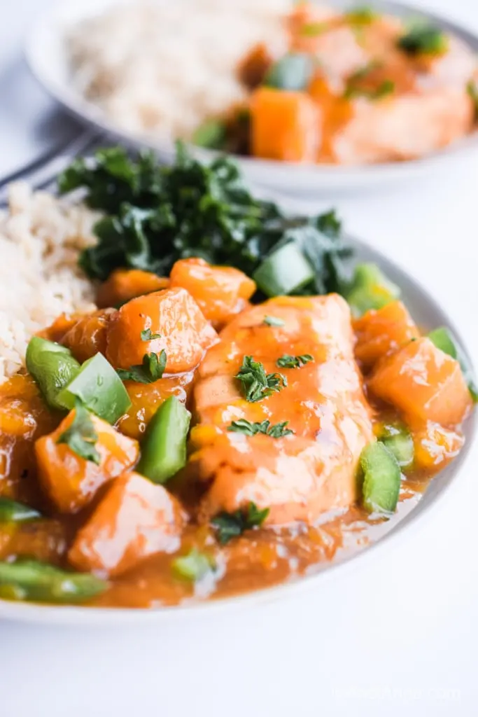 A plate of orange chicken, rice and greens.