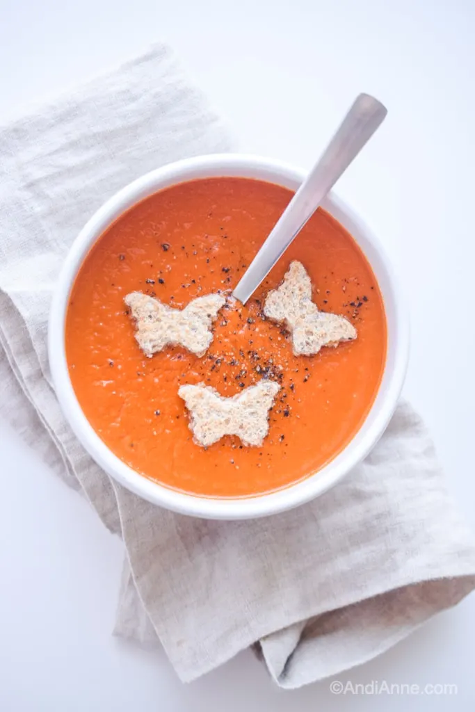 classic homemade tomato soup in a white bowl on a beige napkin