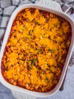 Hamburger casserole with melted cheese on top in a white casserole dish.