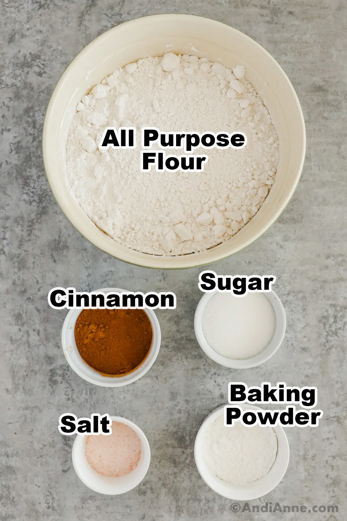 Recipe ingredients including a bowl of flour, bowls of cinnamon, sugar, salt and baking powder,