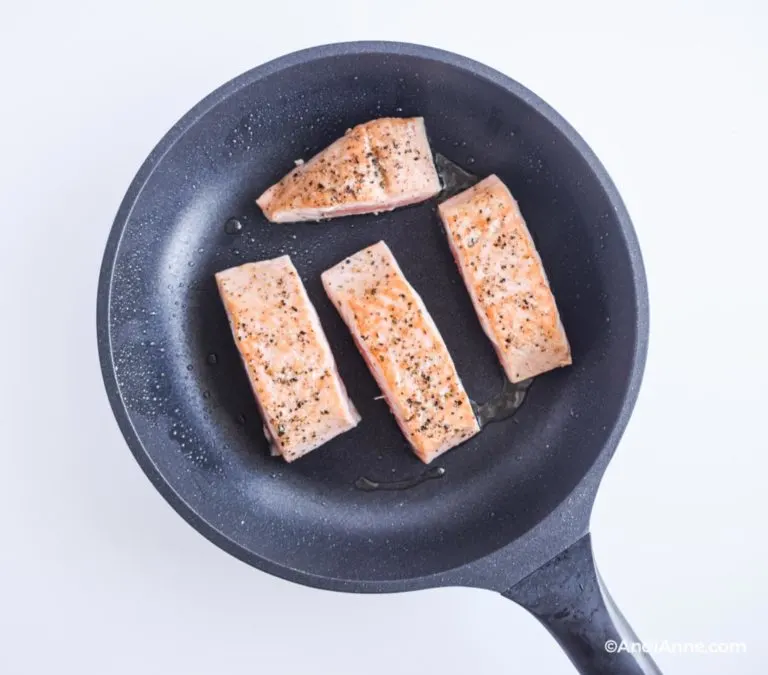 salmon fillets cooking in frying pan, skin side facing down