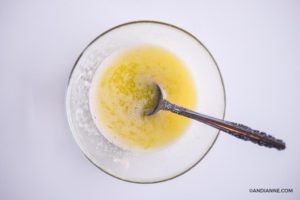 melted butter and minced garlic in glass bowl with spoon