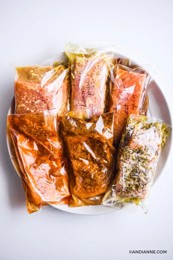 six salmon marinades in plastic bags piled onto a large white plate.
