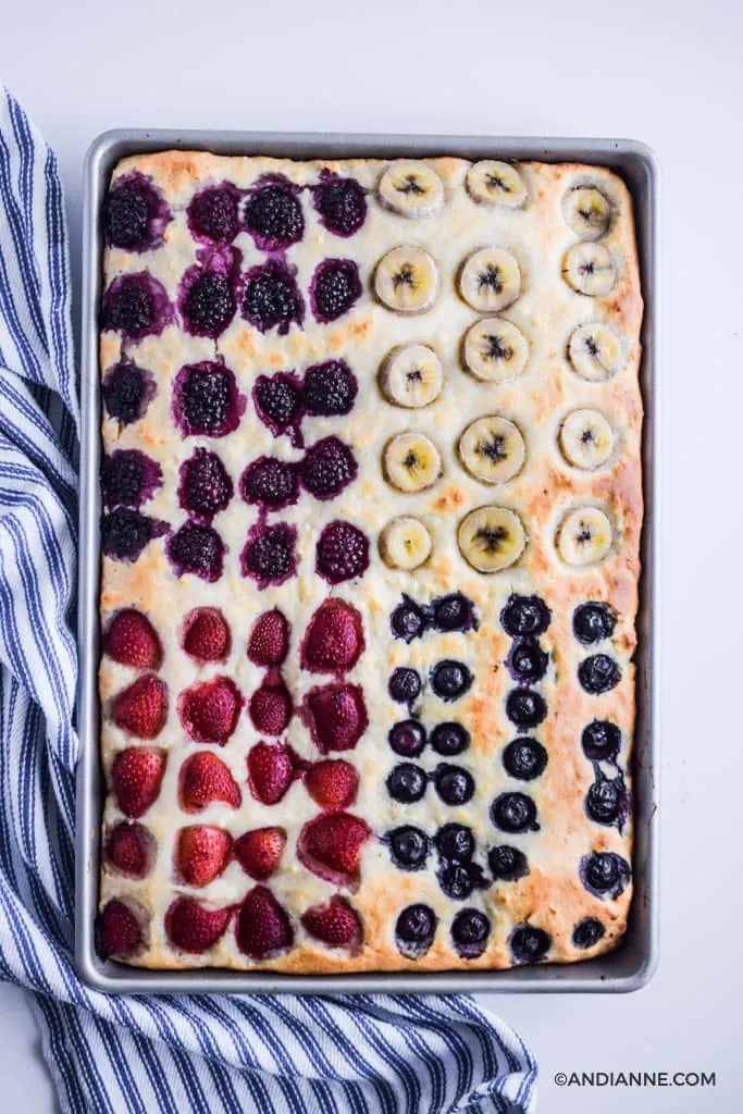 cooked sheet pan pancakes in a baking sheet with striped napkin on left side. 