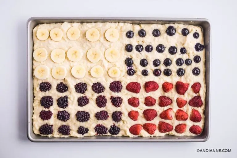 sliced berries and banana pressed into pancake batter in a sheet pan