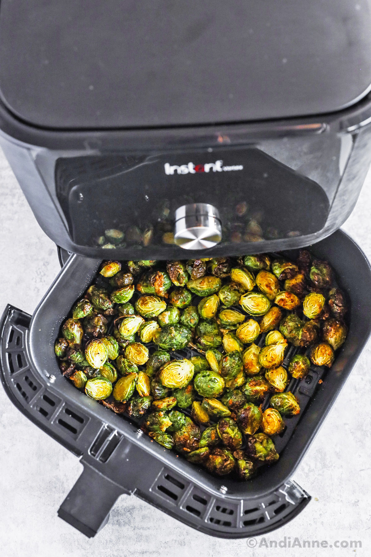 An air fryer with basket open and crispy brussels sprouts inside.