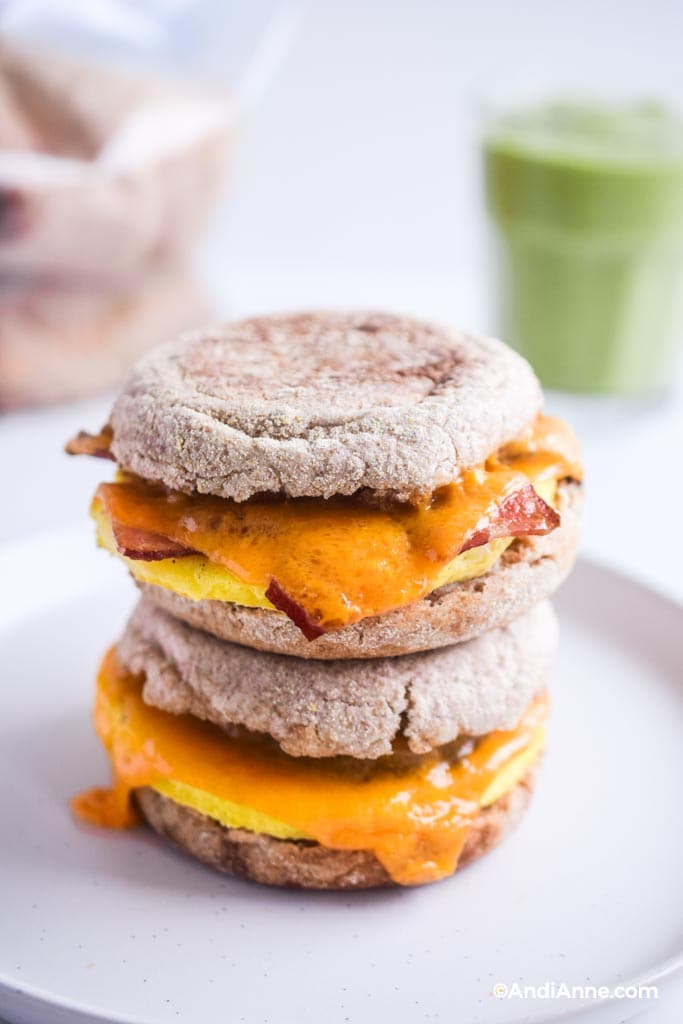 two freezer breakfast sandwiches stacked on top of eachother. Green smoothie in background.
