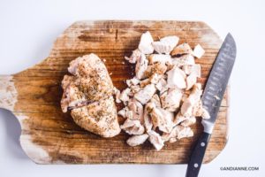 chopped cooked chicken breast on a cutting board with a knife