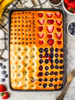 A baking sheet with baked large pancake inside topped with slices of berries and bananas