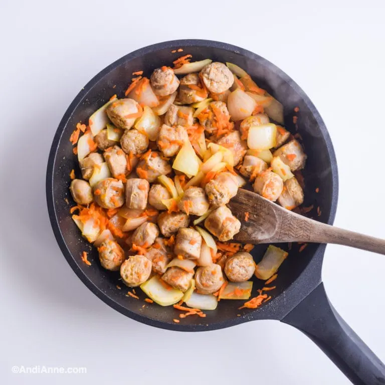 sausage, shredded carrot and pineapple in black skillet