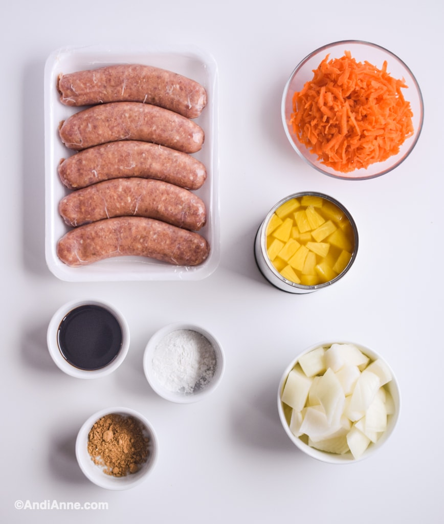 ingredients in small bowls: raw sausage, shredded carrot, pineapple chunks, soy sauce, ginger powder, and chopped yellow onion