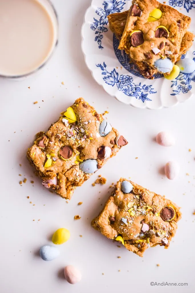 mini egg cookie bars cut out with small white and blue plate and glass of milk on white counter