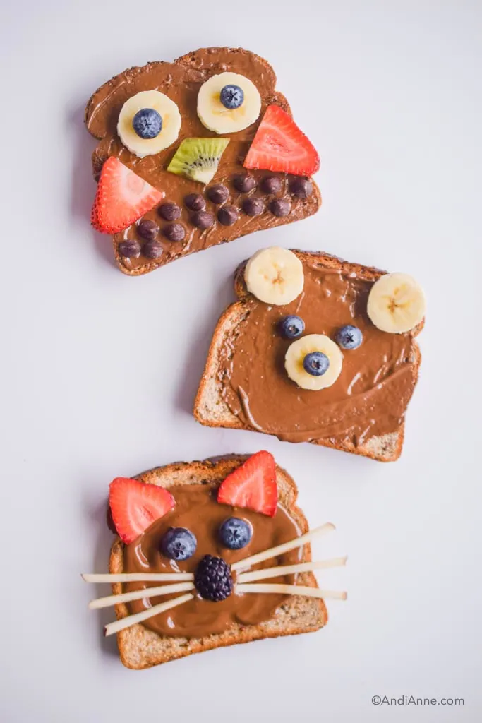 3 animal designed toasts with brown nut butter and fruit to design animal shapes on top