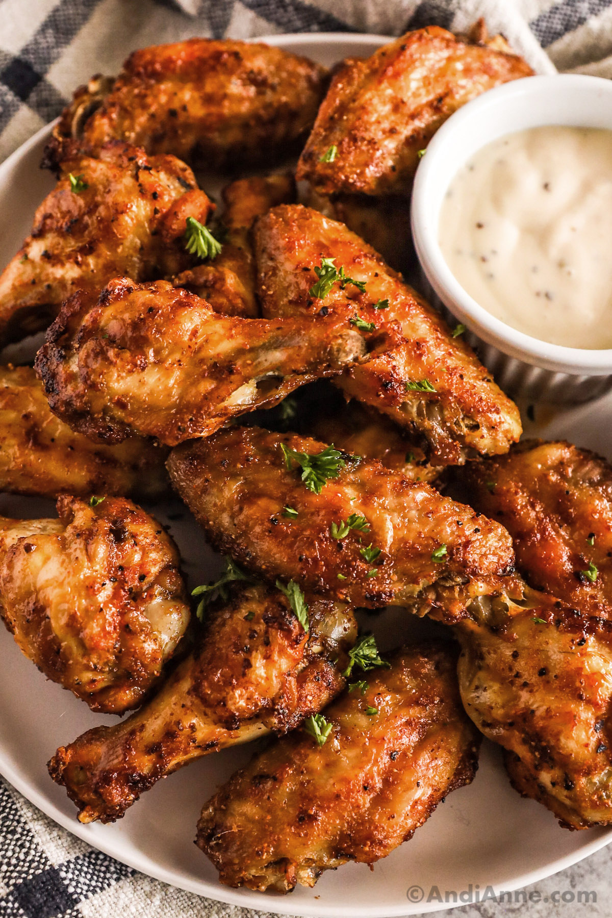 Chicken wings on a plate with a small cup of ranch dressing.