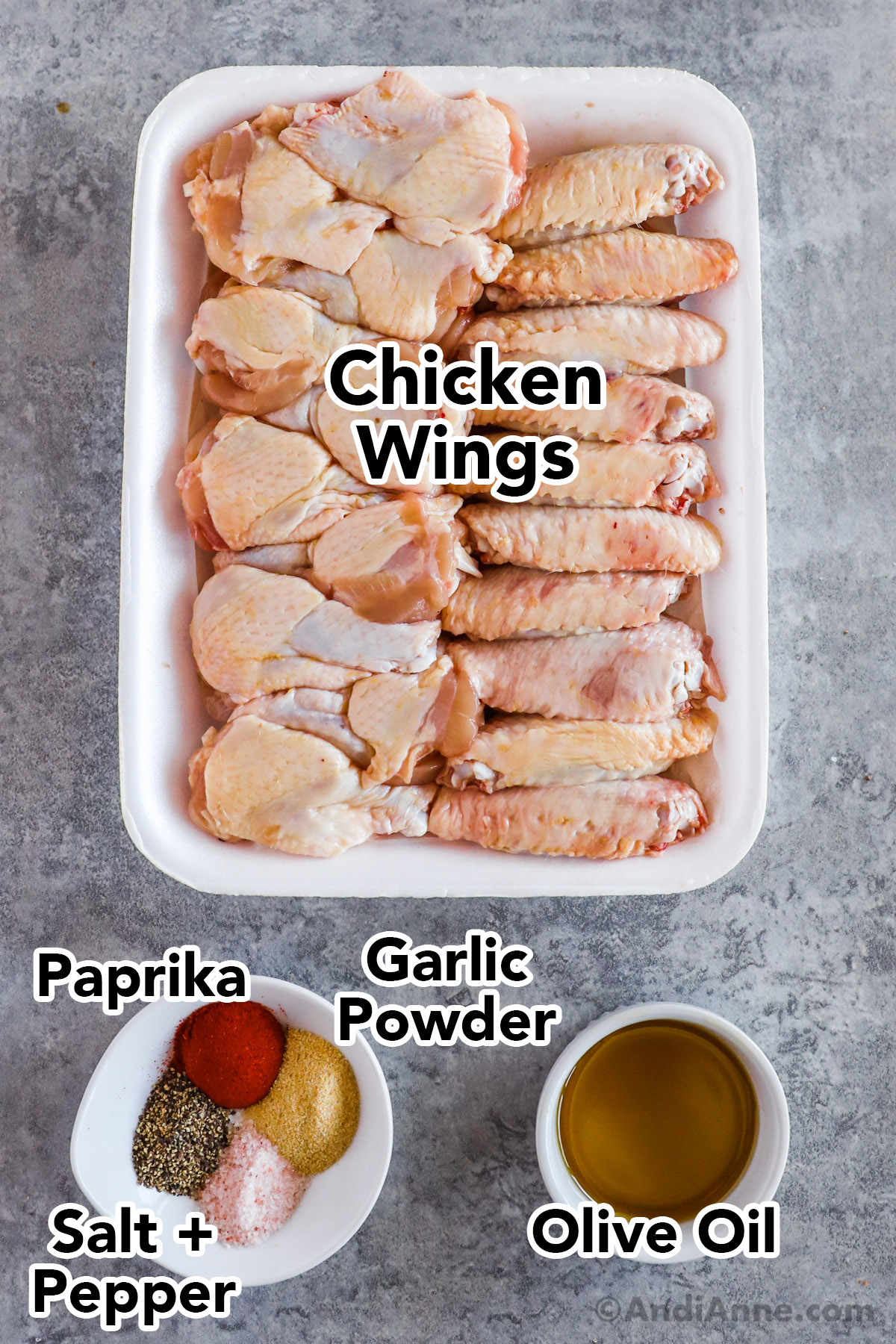 Recipe ingredients including raw chicken wings, bowl of olive oil, and several spices on a small dish.